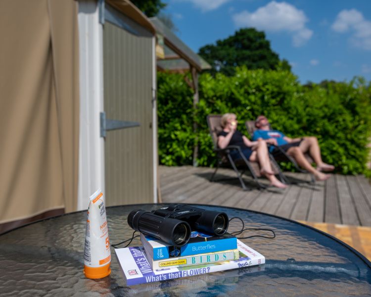 couple relaxing in the sun outside the yurt at back of beyond glamping in dorset