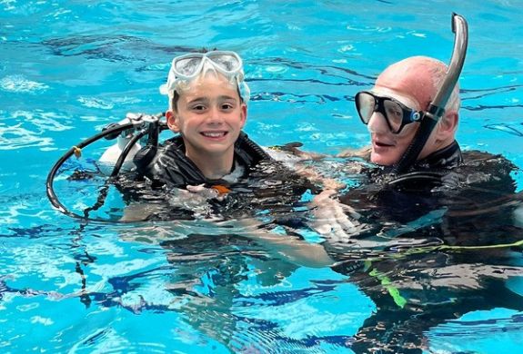 boy with instructor in indoor pool on scuba diving course