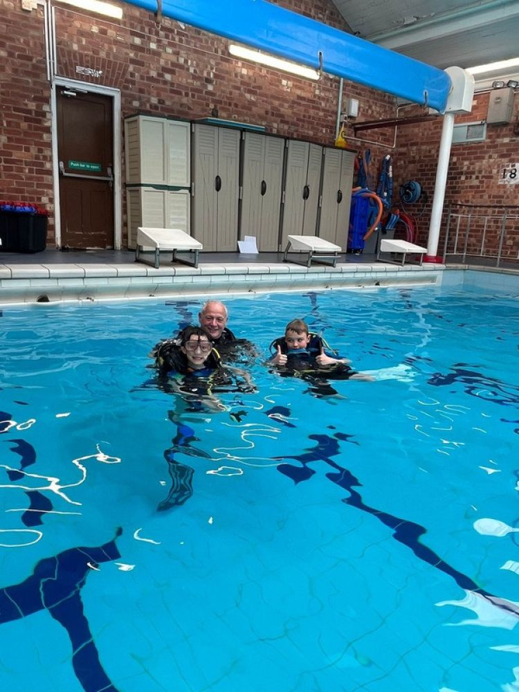 kids with instructor in indoor pool on scuba diving course
