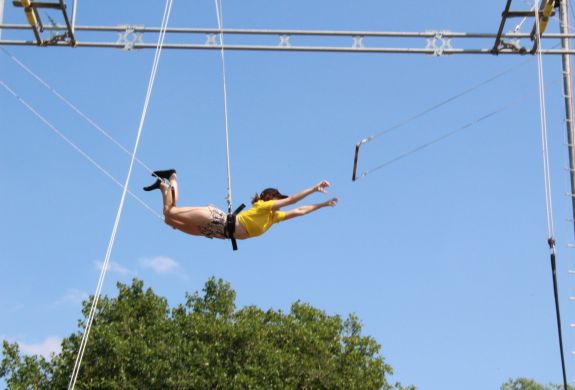 A lady mid air transferring on a trapeze