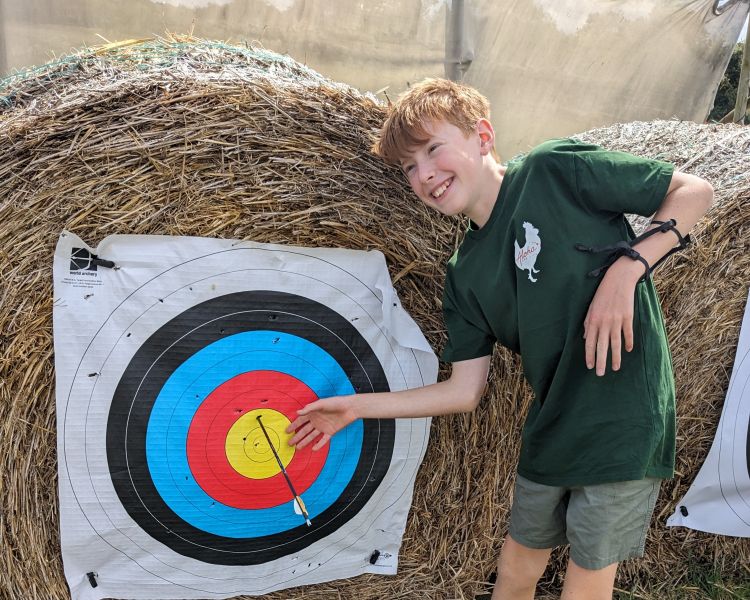 boy showing off a bullseye in archery target