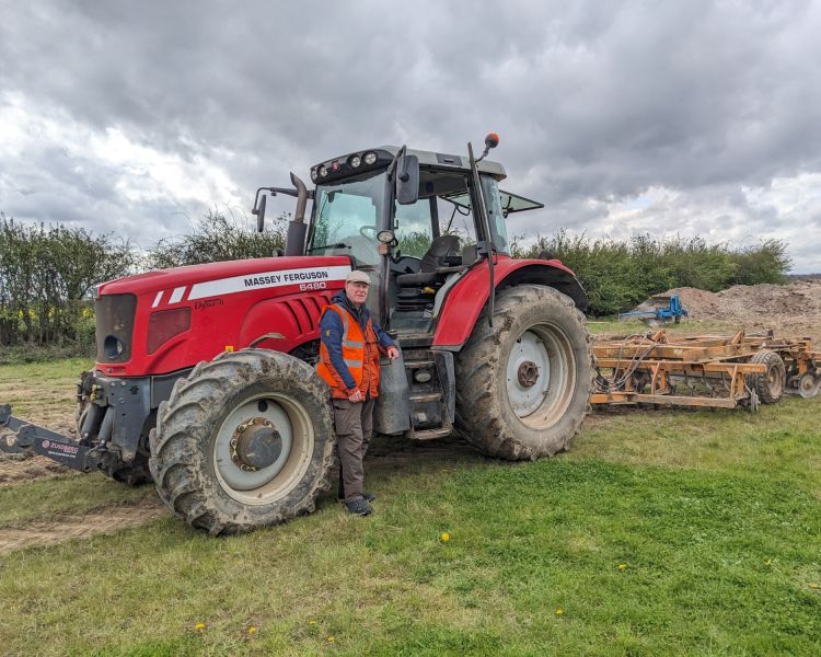 man posing next to tractor on a tractor driving experience