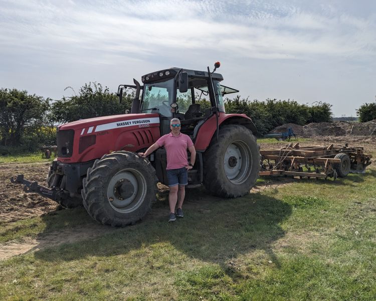 man posing next to tractor on a tractor driving experience