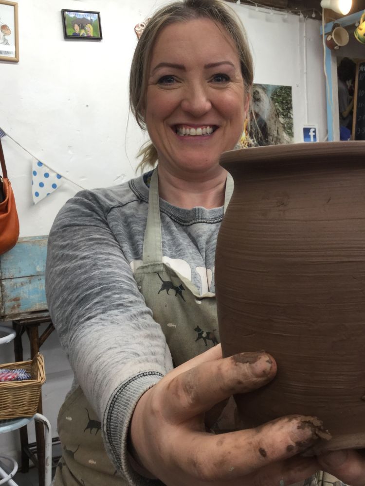 woman holding a clay vase she has made on pottery course experience day