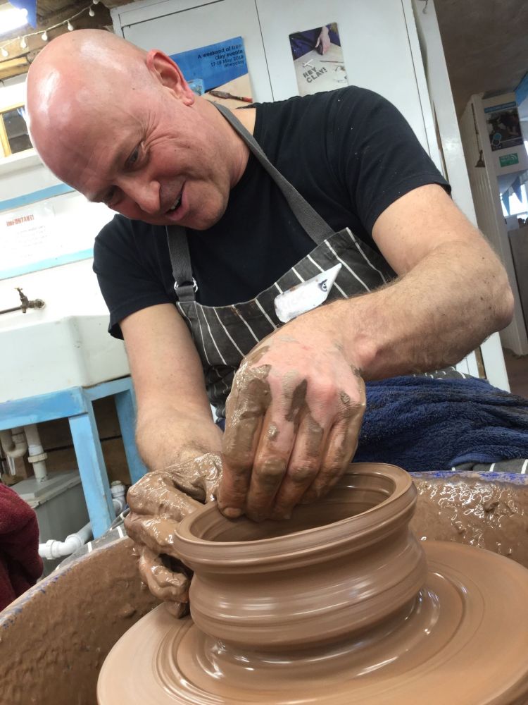 man making a bowl out of clay on a potters wheel on a pottery course experience day