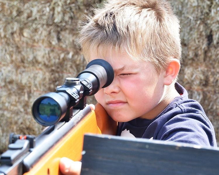 young boy aiming an air rifle on a spy camp experience day for kids