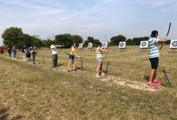 Row of people aiming at targets on archery experience