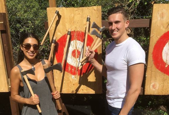 man and woman posing with axes in front of targets on an axe throwing experience