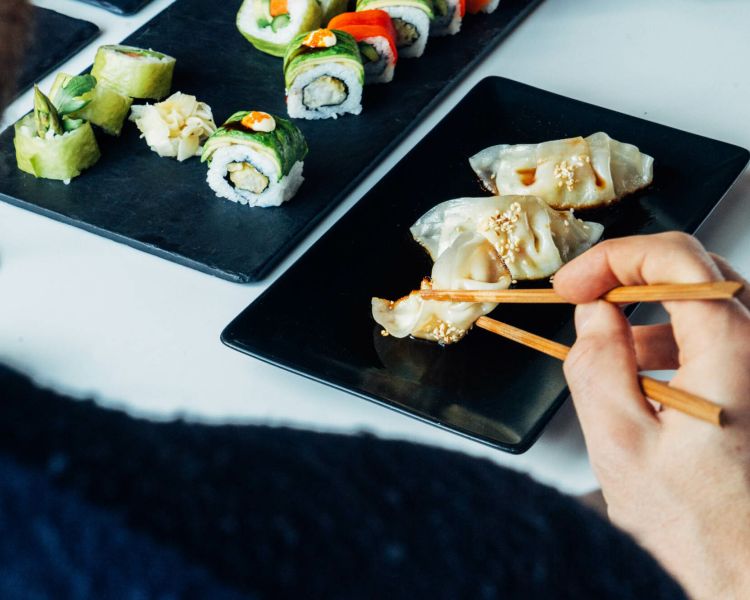 person eating sushi with chopsticks at inamo london