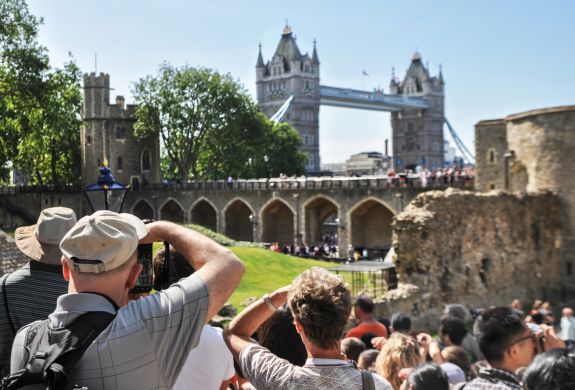 tourists taking photos of tower bridge from inside the grounds of the tower of london