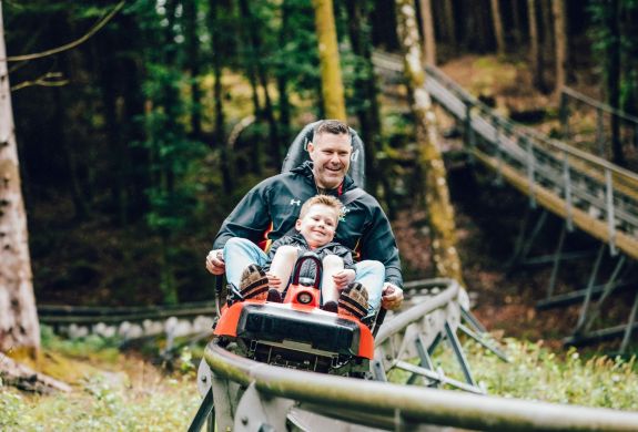 man and youngster on a fforest coaster ride experience through forest