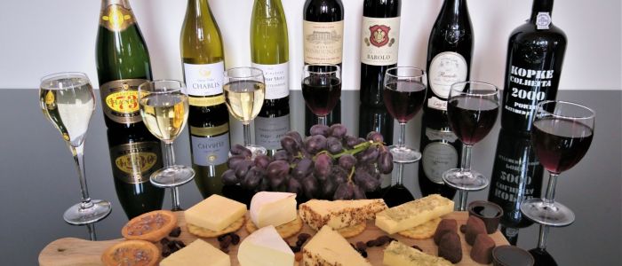 bottles of red wine and port lined up with a platter of cheese and crackers on a wine tasting experience with wine cottage