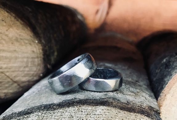 two wedding rings sitting on wooden logs