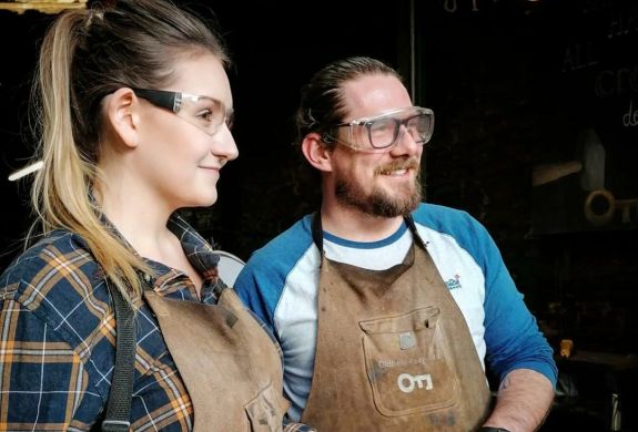 man and woman holding knives they have made on a just for fun blacksmith experience