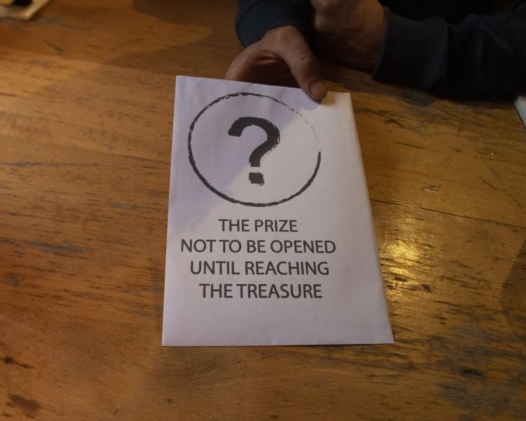 hand holding a piece of paper with instructions for a treasure hunt experience