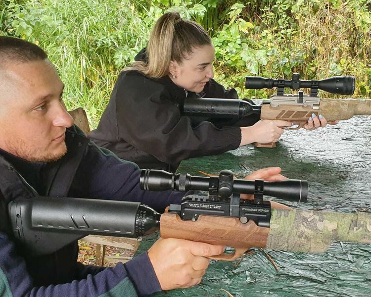 a man and woman sitting at a table shooting air rifles on an air rifle shooting experience day