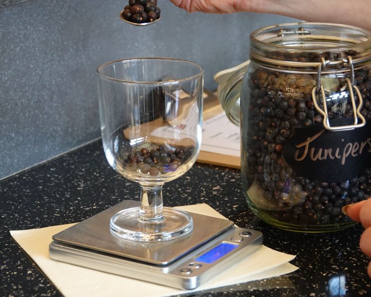 weighing juniper berries in a glass on a gin making experience in shropshire