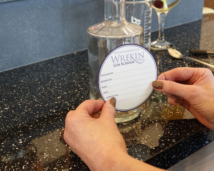 putting label on a bottle of gin made on a gin making experience in shropshire