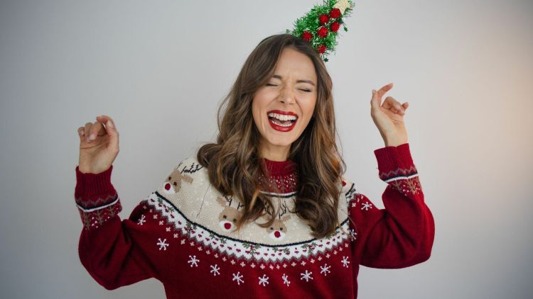 Woman dancing wearing christmas jumper and christmas tree headband