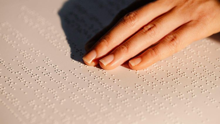 Hand touching braille text panel