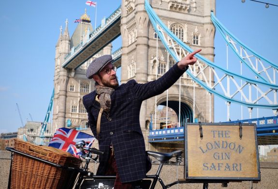 man with vintage bicycle in front of tower bridge on a london gin bike tour