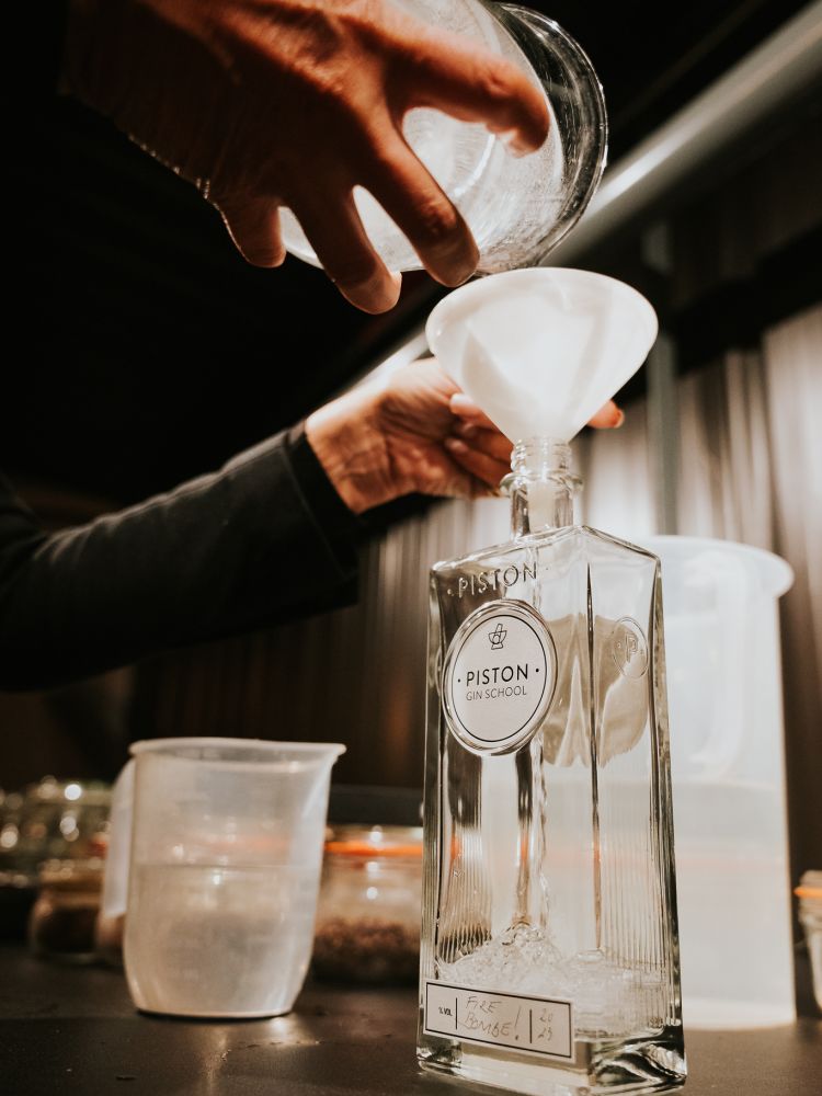 person pouring gin into bottle on gin making experience in cheltenham