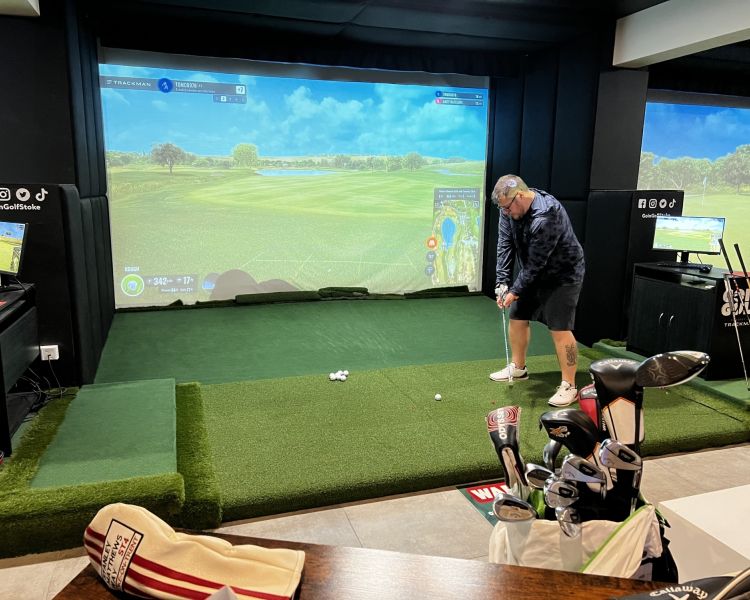 A man setting up on the virtual golf experience