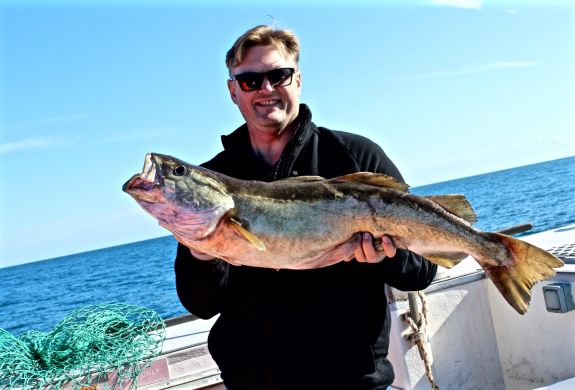 a man holding a fish caught on a deep sea fishing trip off the east sussex coast
