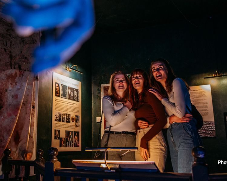 three girls looking at a scary exhibit of a monster at the house of frankenstein in bath