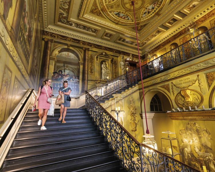 two women walking down a grand ornate staircase in buckingham palace