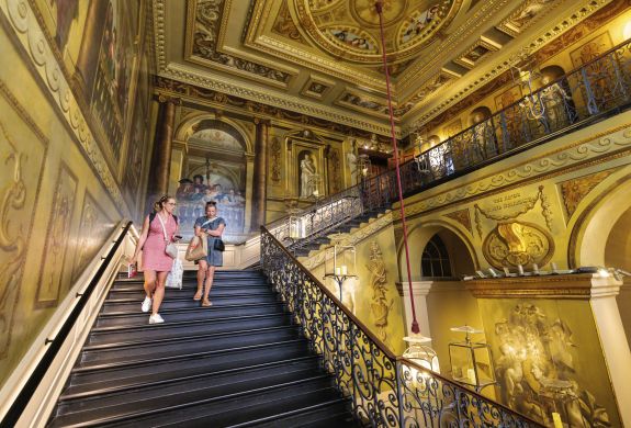 two women walking down a grand ornate staircase in buckingham palace