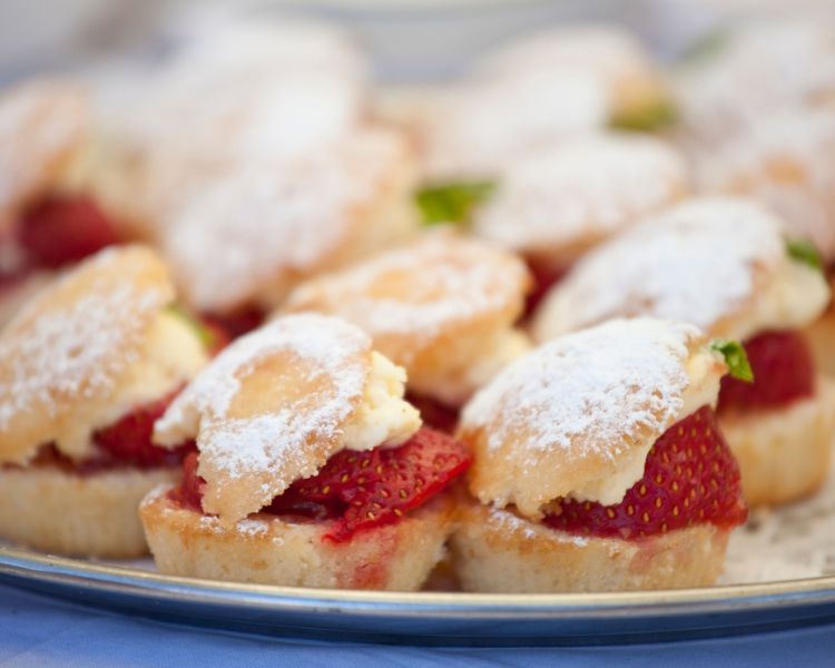 a plate of scones filled with jam and cream