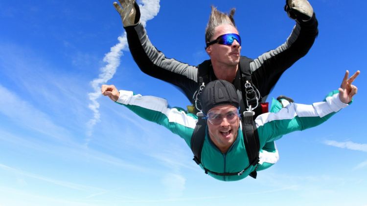 a woman on a tandem skydive during freefall against a blue sky