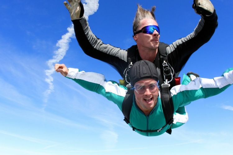 a woman on a tandem skydive during freefall against a blue sky
