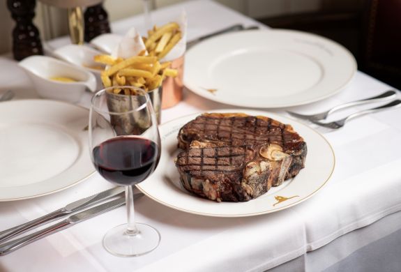a steak meal with fries on the side and a glass of wine at marco pierre white's london steakhouse company