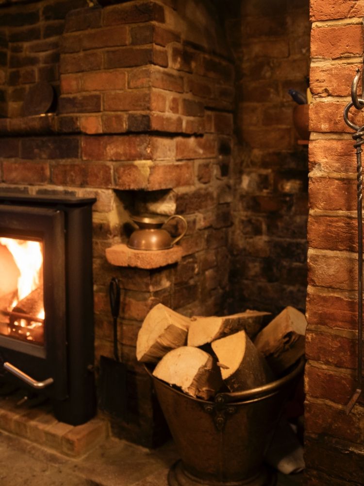 a wood burning stove with a cast iron poker hanging on the wall next to it