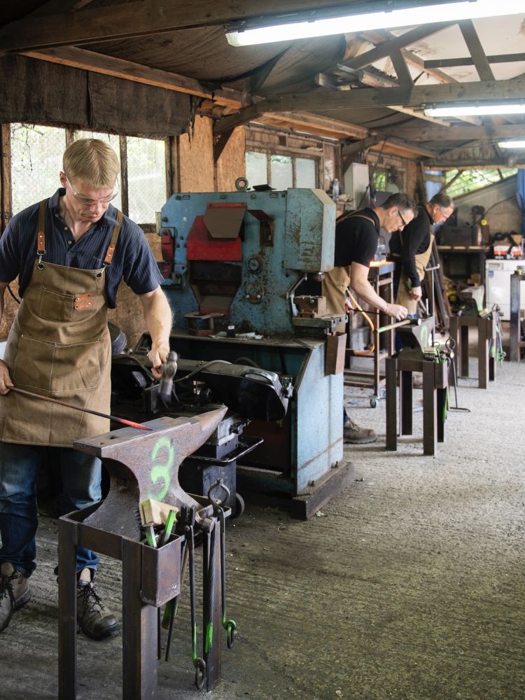 people in a forge workshop working on making a poker on a blacksmith experience