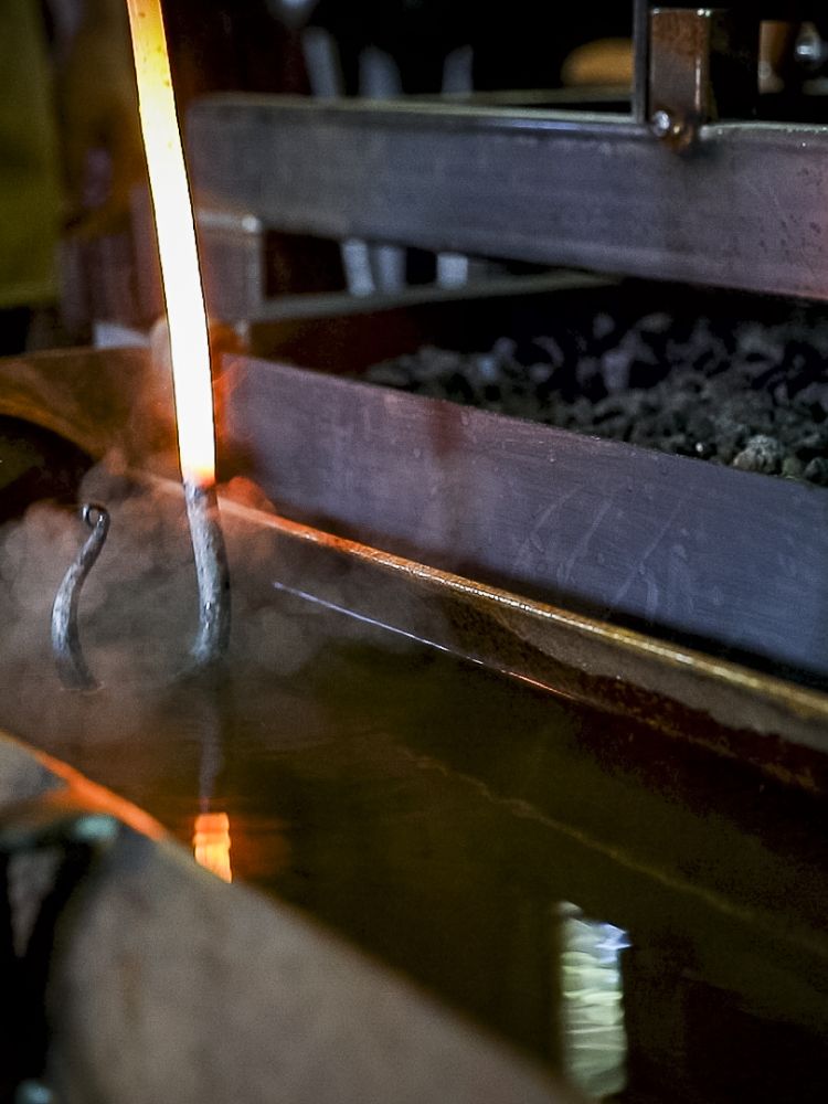 the head of a poker being dipped in cold water to cool it down on a blacksmith experience