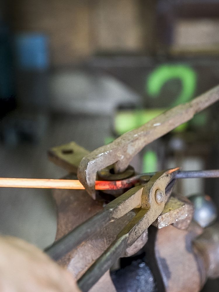 a close up of the head of a poker being bent while the metal is hot on a blacksmith experience