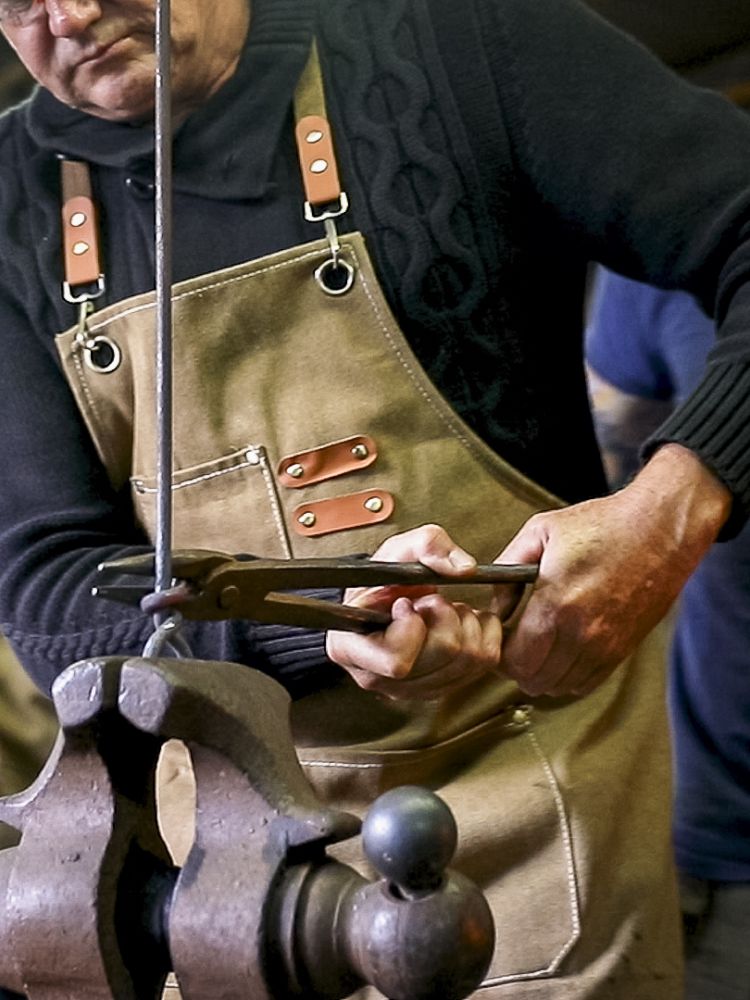 man working on making a poker on a blacksmith experience being watched by the instructor