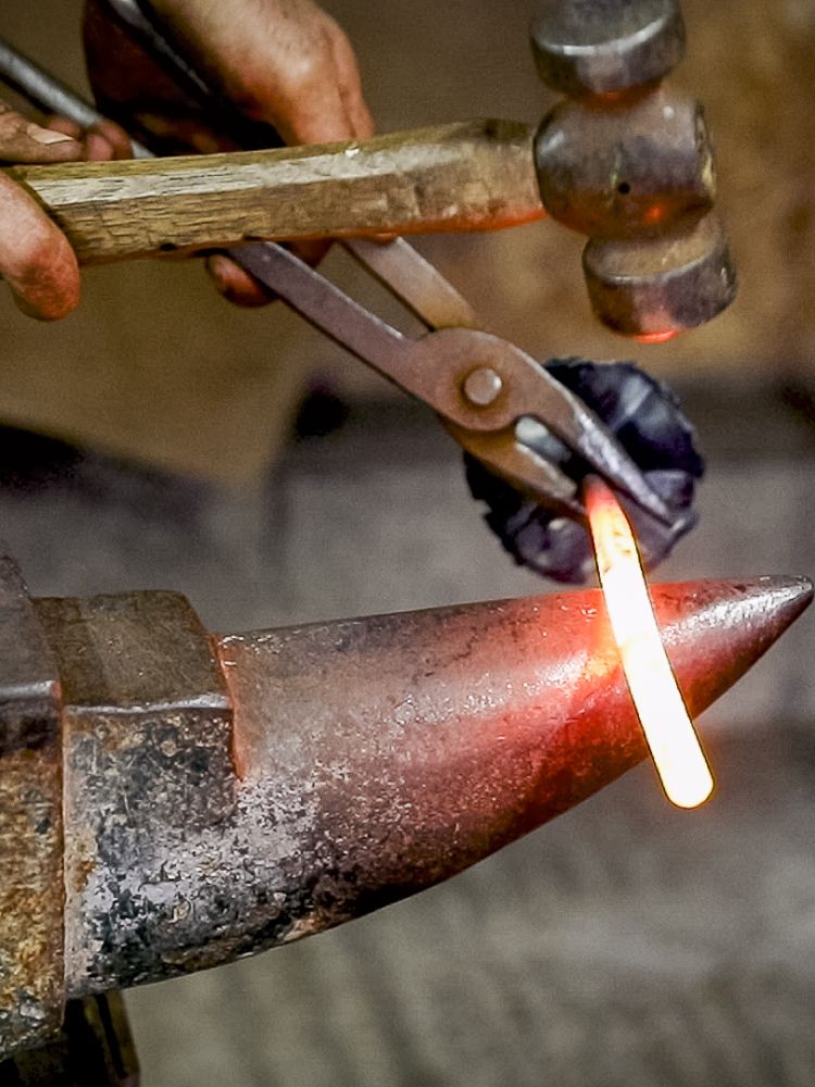 part of a tealight holder being hammered into shape on a blacksmith experience