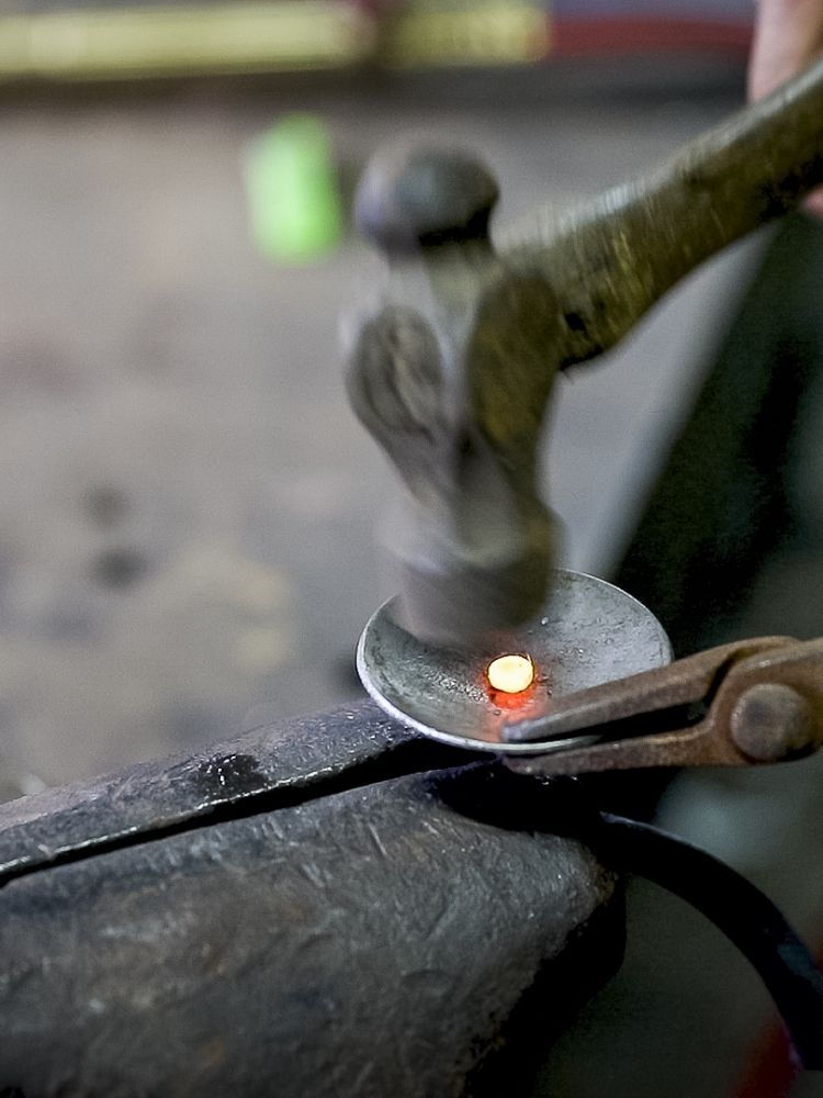 part of a tealight holder being hammered into shape on a blacksmith experience