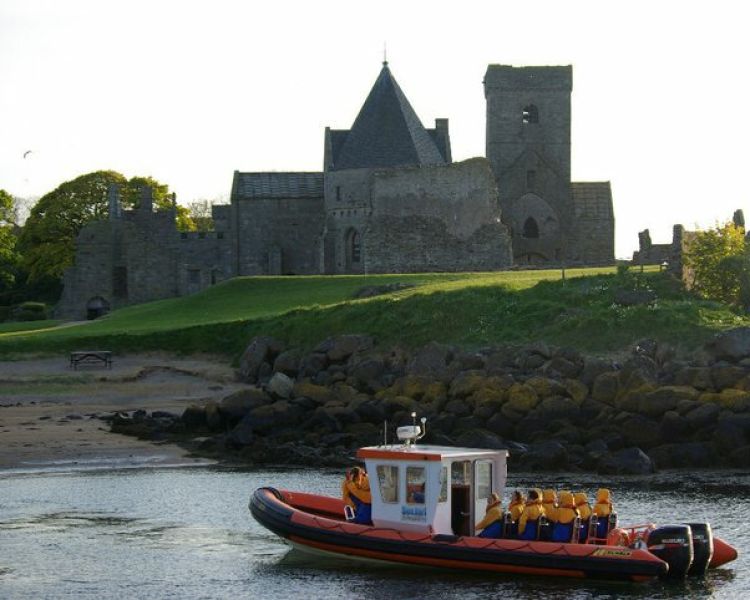 passengers on a boat trip looking at an old church on one of the islands seen on the high speed boat trip from south queensferry on scotland
