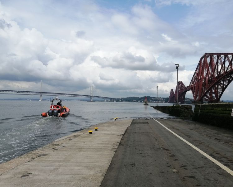 view of a high speed boat sailing off next to one of the forth bridges on a high speed boat trip from south queensferry in scotland