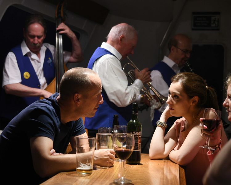 people chatting and drinking on an evening themed sightseeing cruise in scotland