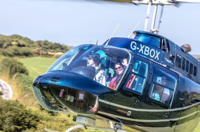 a black helicopter taking off for a helicopter tour with a person waving through the window