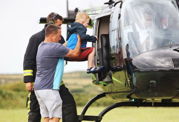 a man helping a child into a helicopter as part of a helicopter family experience