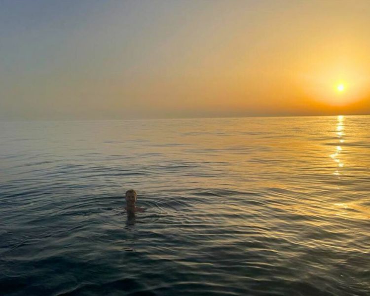 Man swimming in the sea with the sun setting