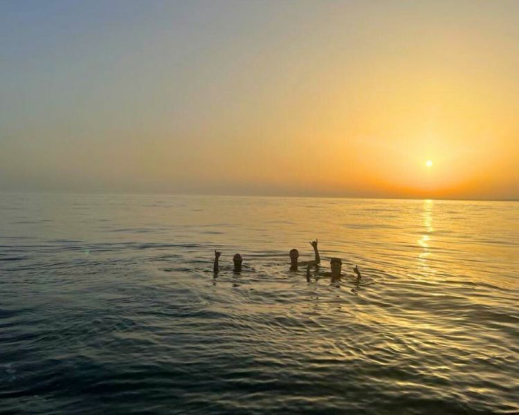 Group of people in the sea with the sun setting