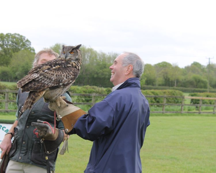 a man handling a large owl with demonstrator looking on as part of a falconry experience day